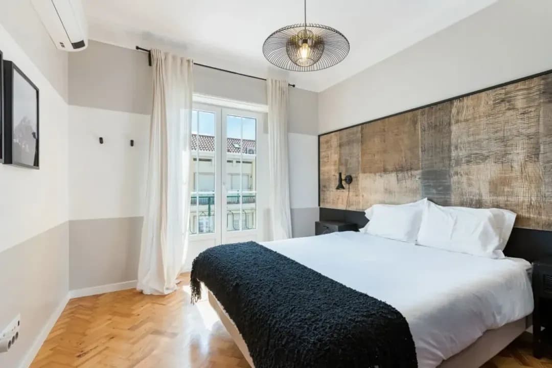 Quarto com cabeceira em madeira reaproveitada e portas de varanda francesas na Alvalade Gallery